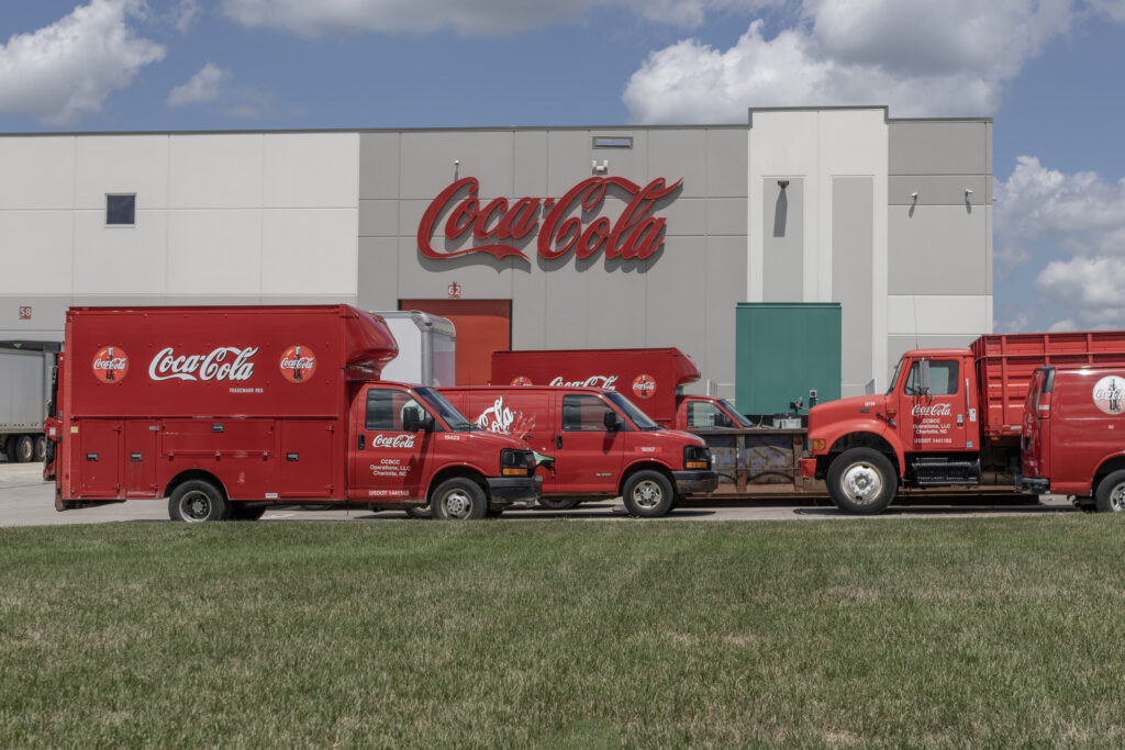 Coca-Cola plant with delivery trucks in front, illustrating value-based pricing and consumer perception in different markets.